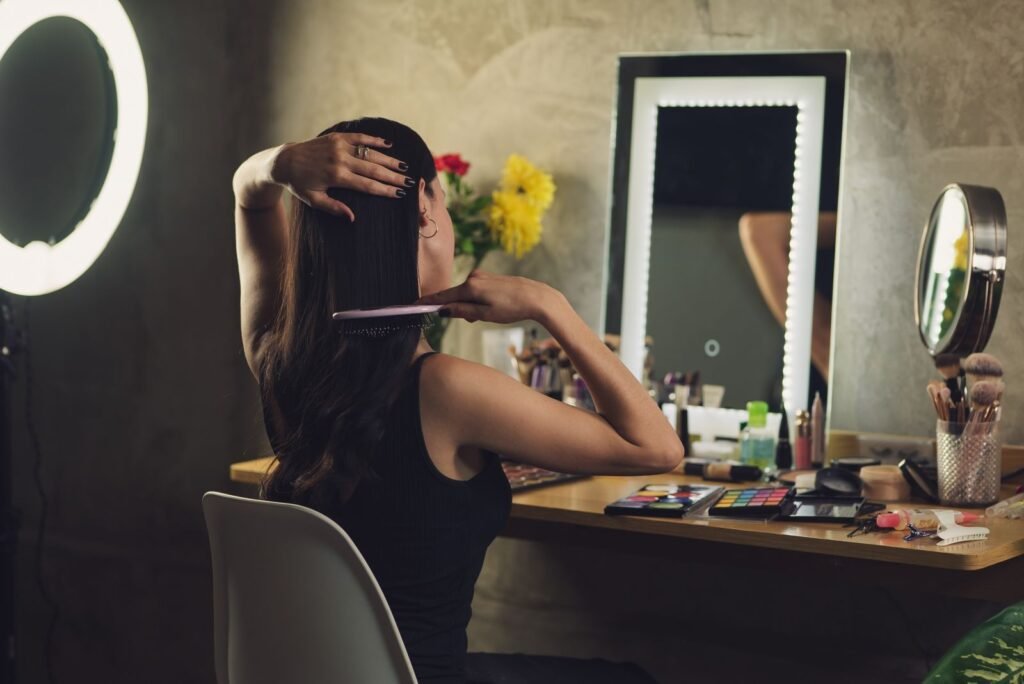 Woman combing her hair at a mirror while reading about hair shedding and thinning hair