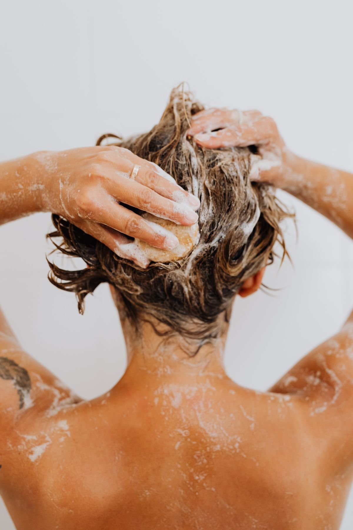 Back view of hair covered in shampoo foam during a scalp wash