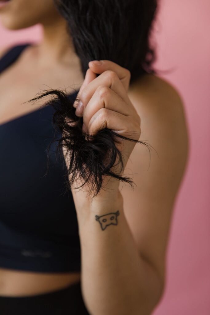 Close-up of a hand holding the dry, frayed ends of dark hair, showing hair breakage