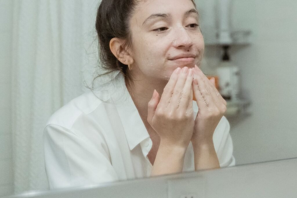 Woman applying moisturiser while looking in a bathroom mirror